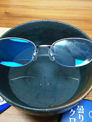 黒い器の上に眼鏡。右側に細かい水滴。