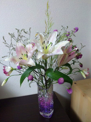 ウォータービーズを入れた花瓶にユリなどの花が活けられている。